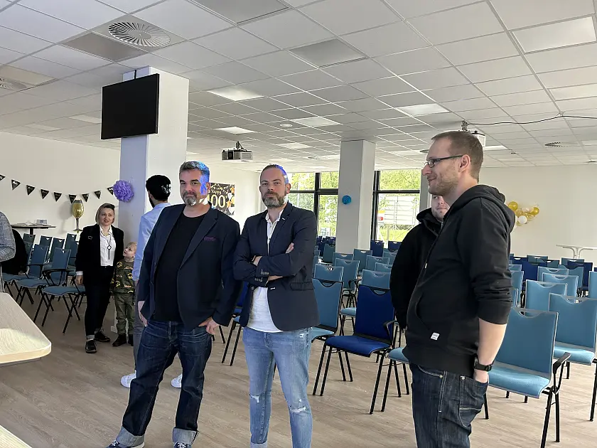 Gl&uuml;ckliche Personen stehen gemeinsam in der Aula